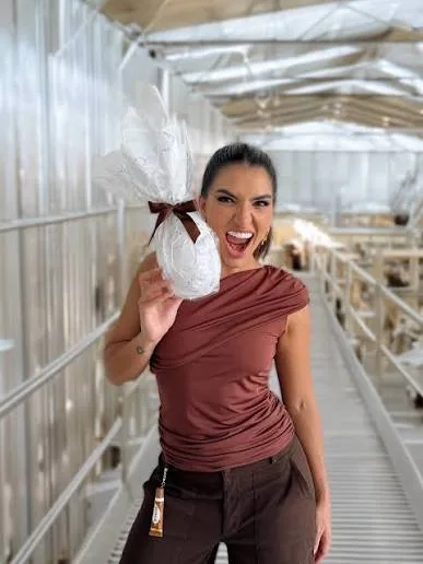 Letícia Vaz holding a white Easter package tied with a brown ribbon.
