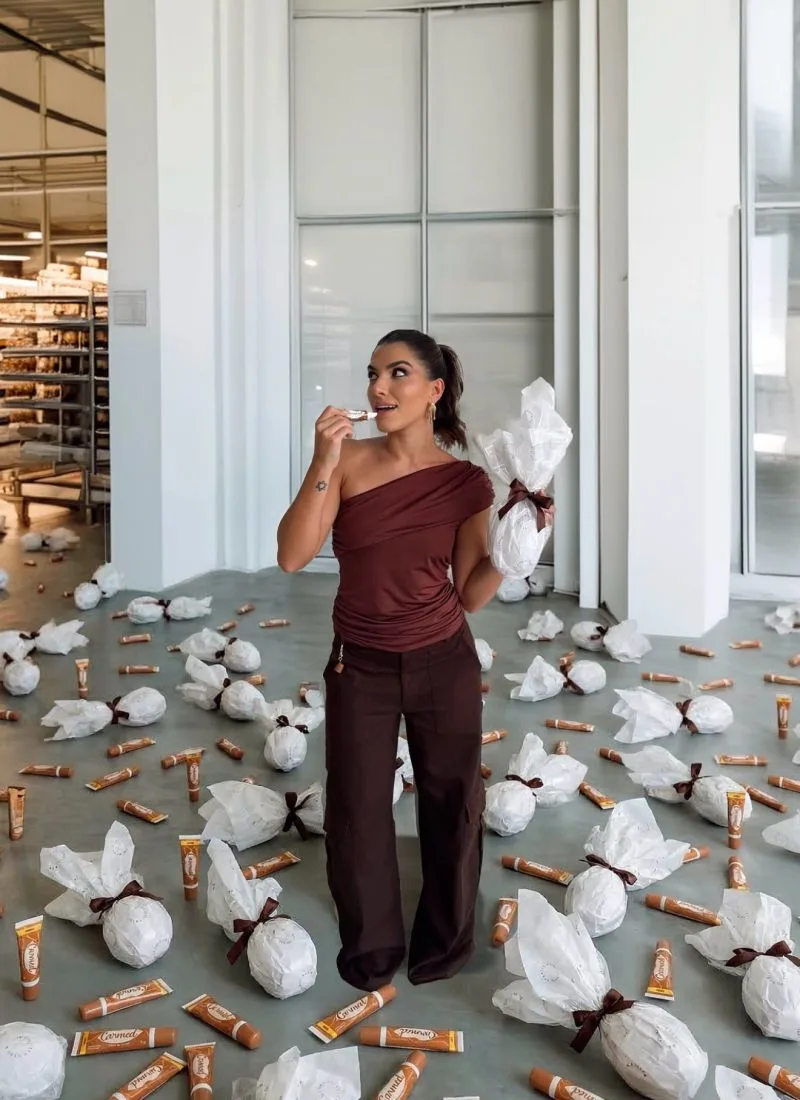 Letícia Vaz holding an Easter egg-shaped package among wrapped packages for the LV Store campaign.