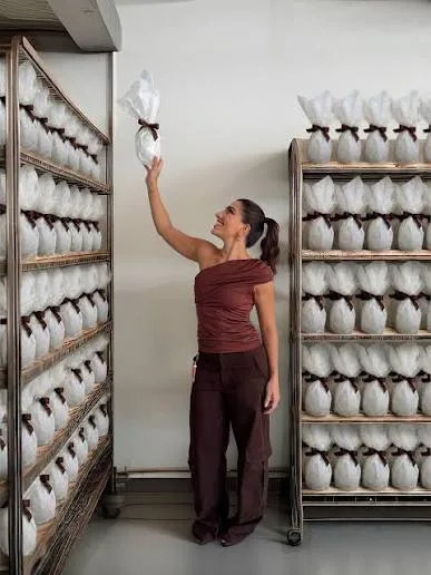 Letícia Vaz between factory racks filled with Easter egg-shaped packages.